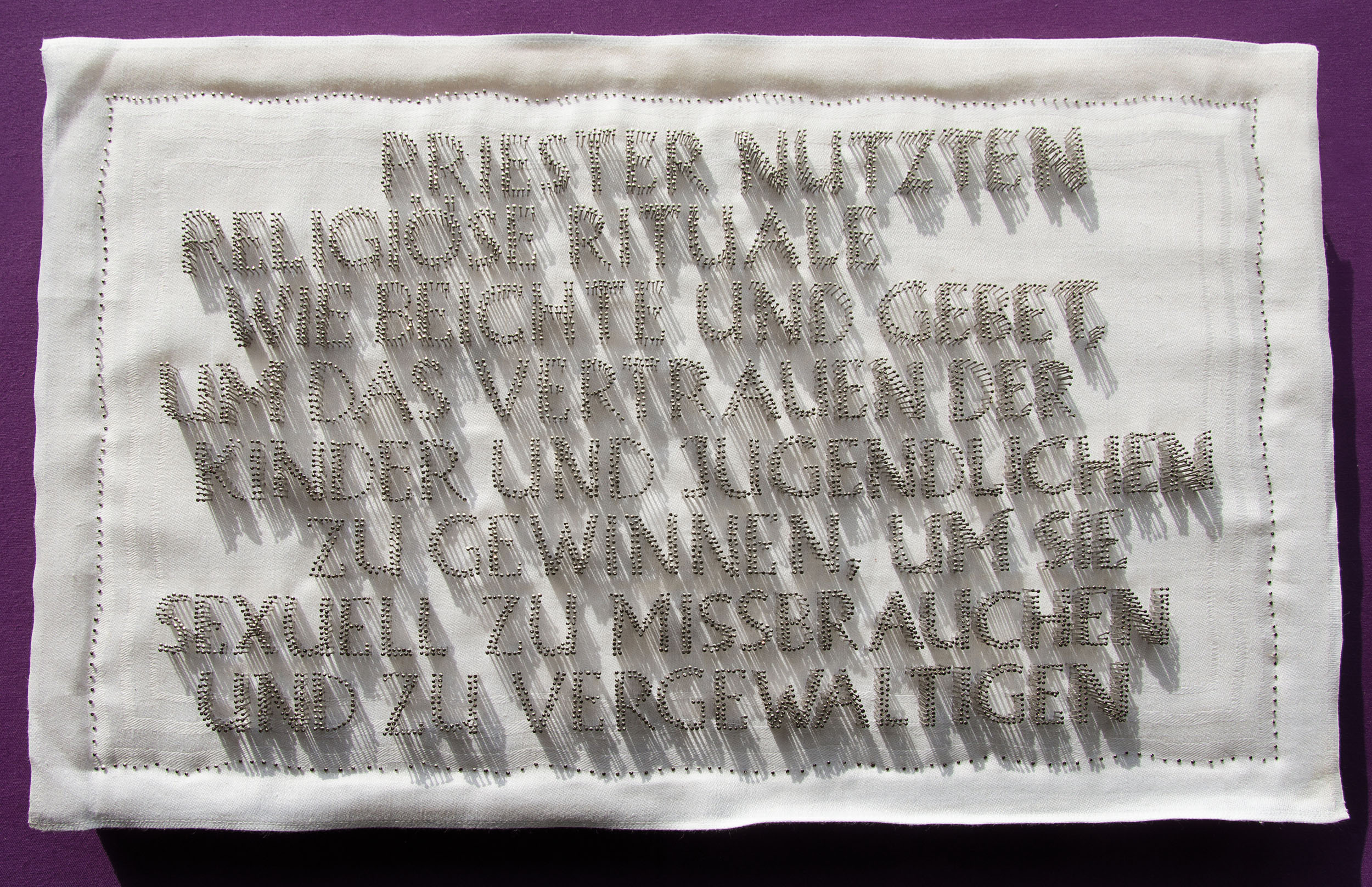 7.000 Stecknadeln formulieren einen Satz: 'Priester nutzten religiöse Rituale wie Beichte und Gebet, um das Vertrauen der Kinder und Jugendlichen zu gewinnen, um sie sexuell zu missbrauchen und zu vergewaltigen